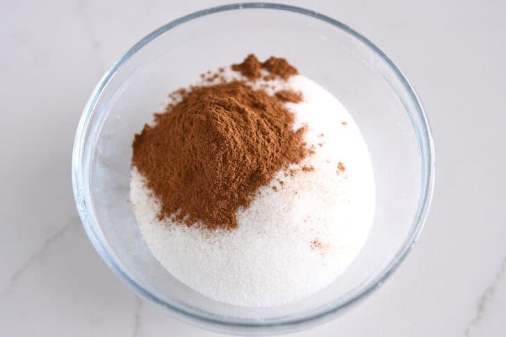 Small glass bowl with granulated sugar and ground cinnamon.