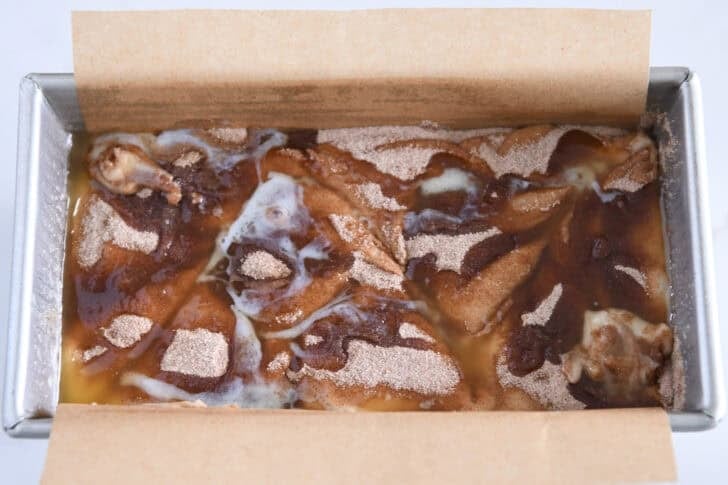 Loaf pan with quick bread batter, cinnamon swirls and melted butter.