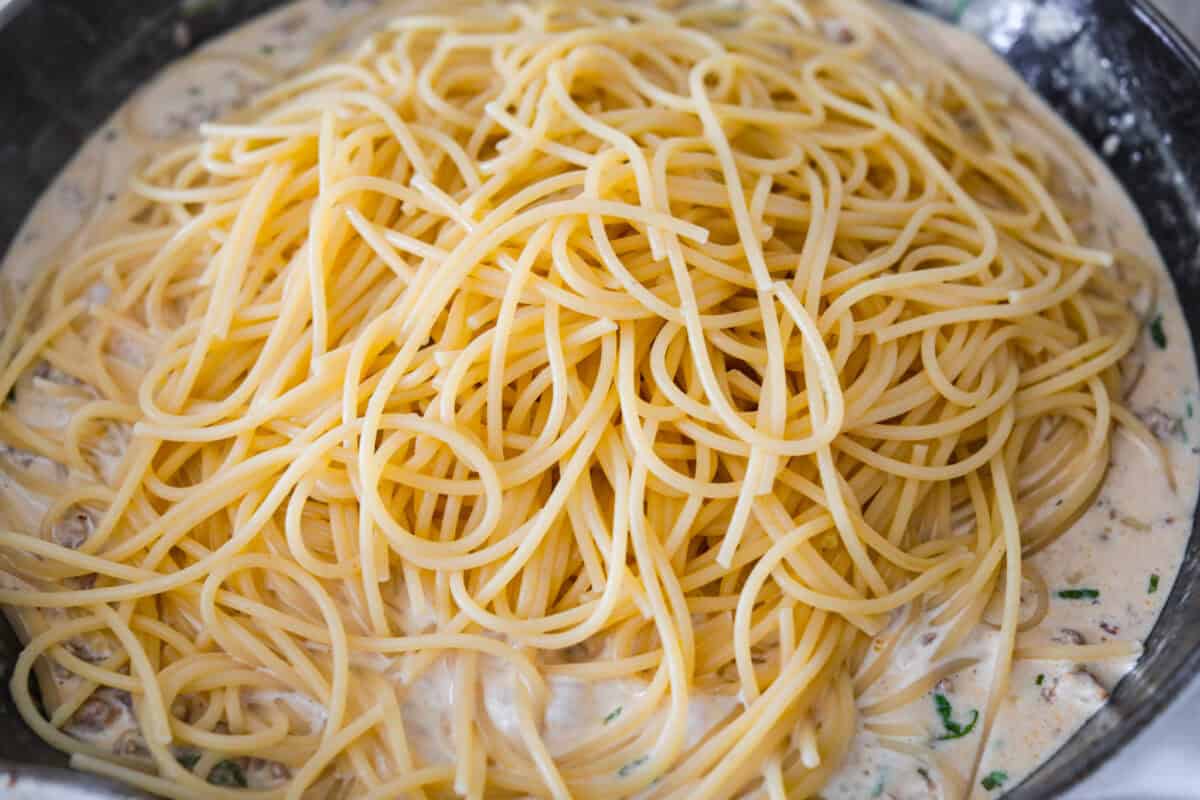 Cooked spaghetti added to the skillet. 