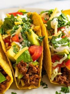 ground beef taco recipe showing stuffed tacos loaded with toppings.