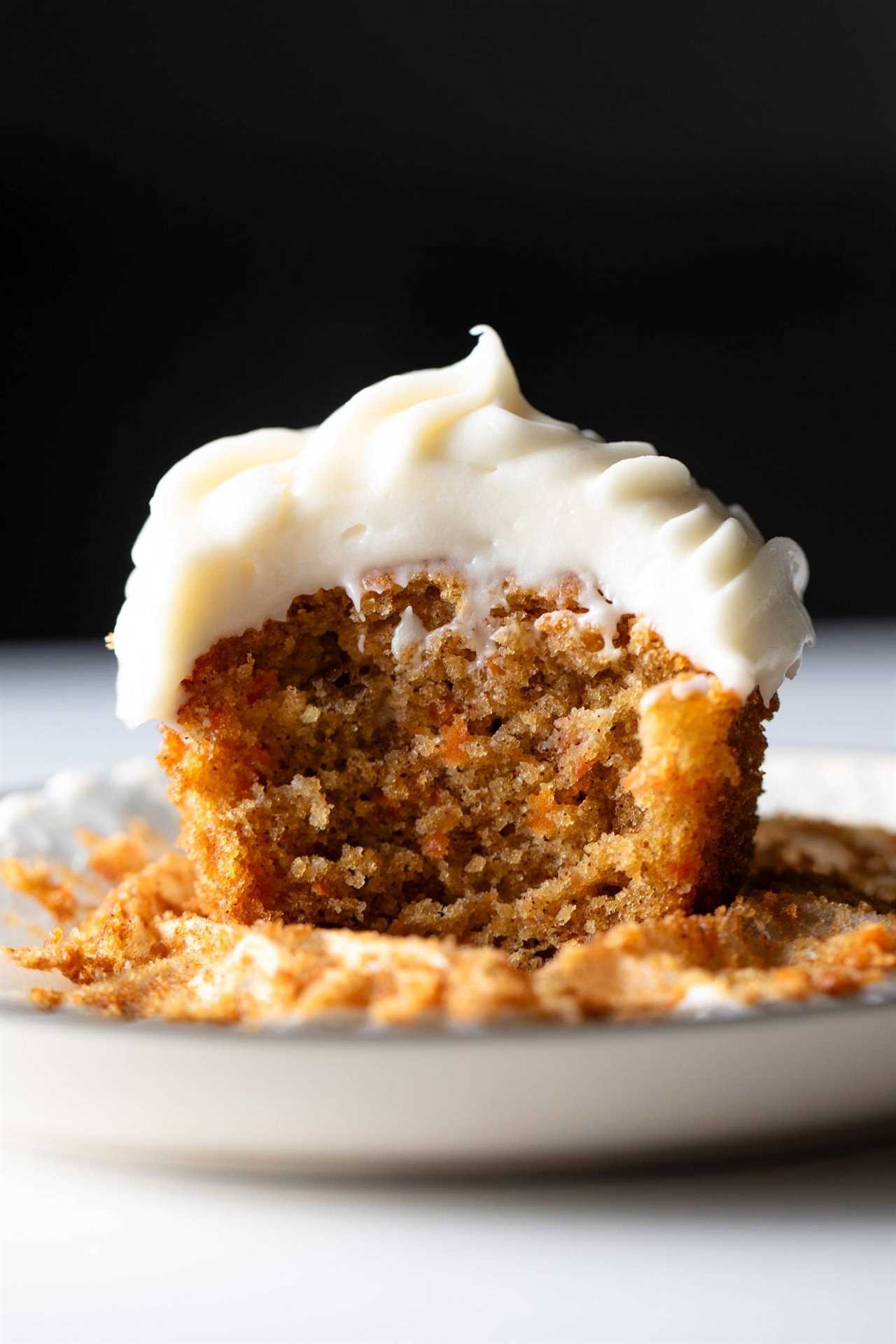 Carrot cake cupcake with cream cheese frosting on a plate.
