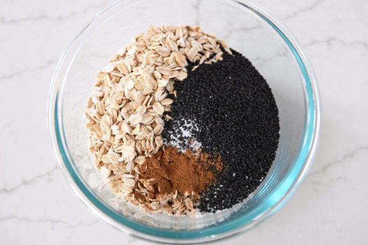 Glass bowl with basil seeds, oats, cinnamon, and salt.
