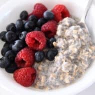 White bowl with chia oats, blueberries, and raspberries.