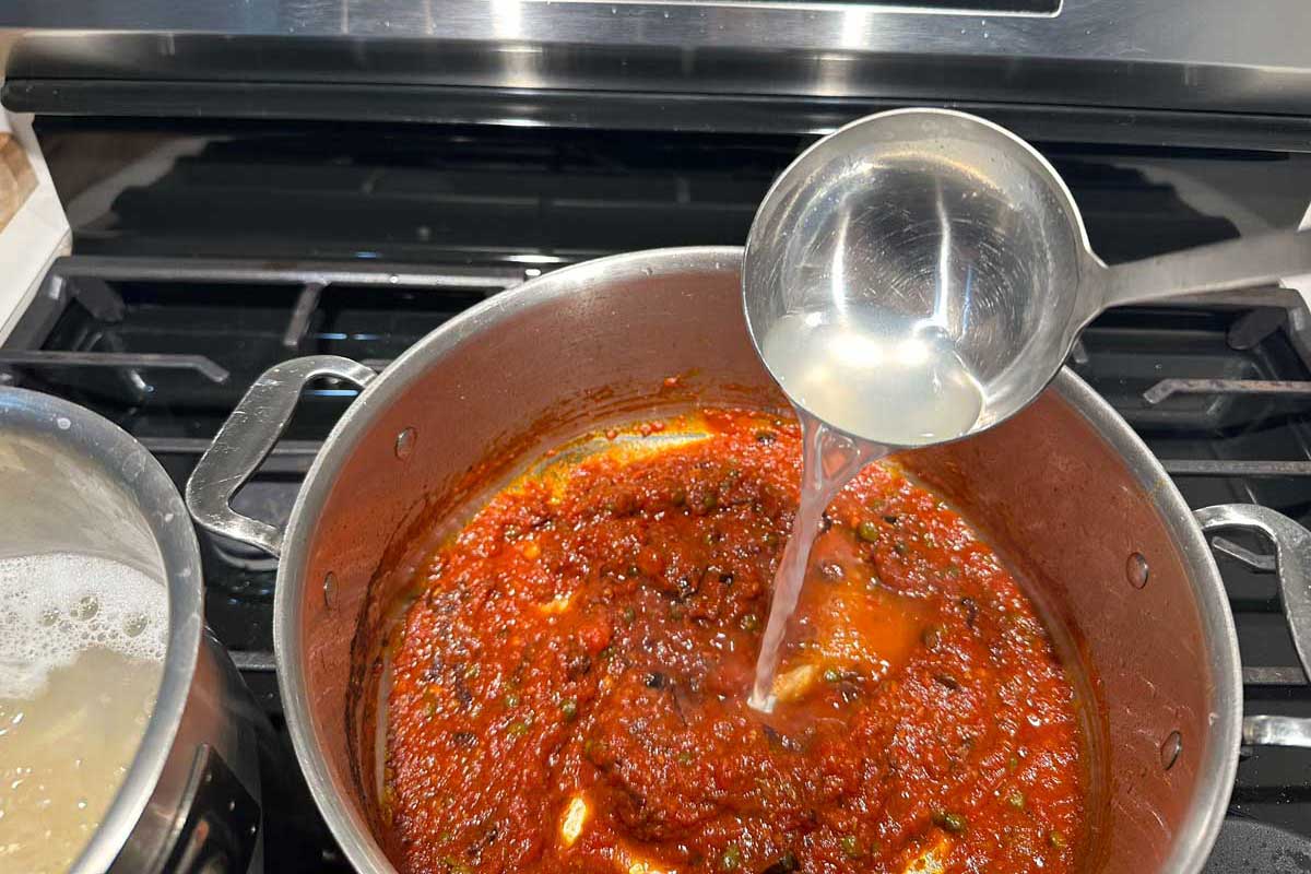Authentic Italian marinara sauce cooking — San Marzano tomatoes slow-simmering in cold-pressed olive oil with garlic