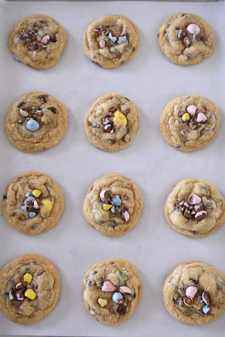Top down view of cookie sheet with 12 baked cadbury egg chocolate chip cookies.