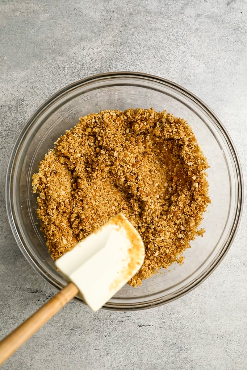 medium glass bowl spatula combining brown sugar, melted butter and nilla wafer crumbs