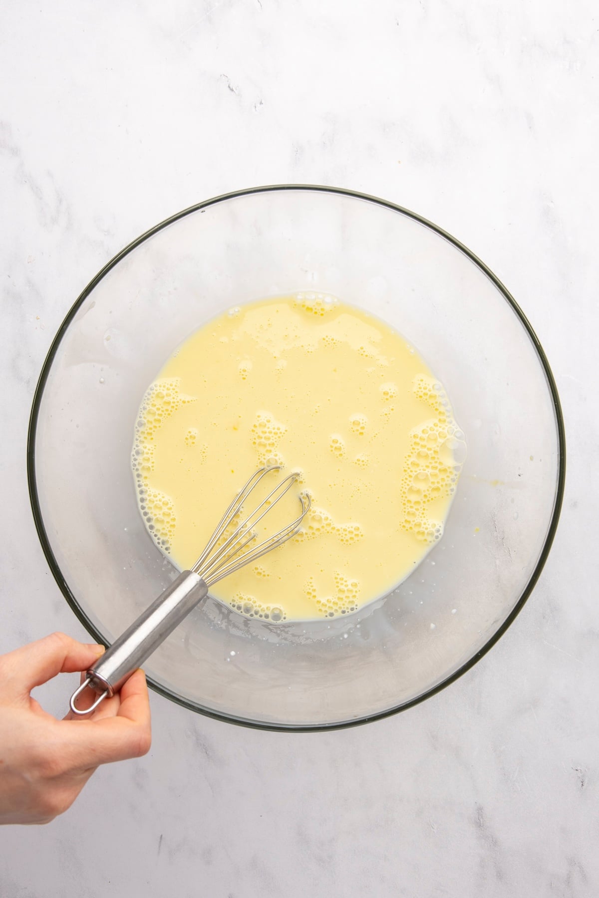 whisking milk and eggs together in large bowl