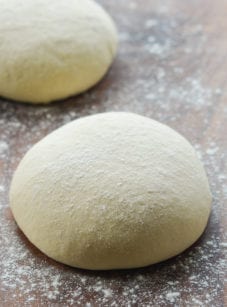 Ball of pizza dough on a floured surface.