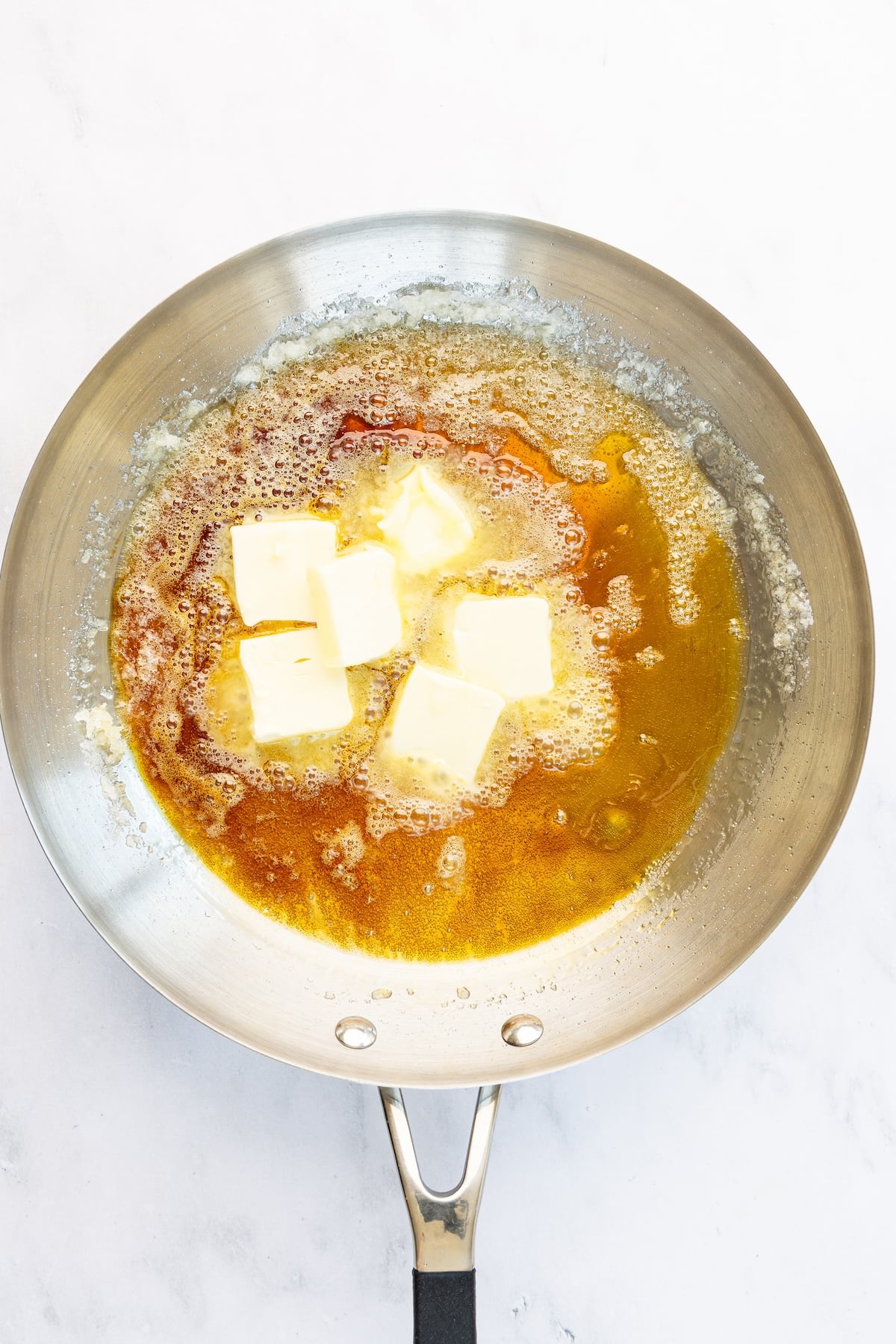 12-inch skillet with butter chunks in sugar/water mixture