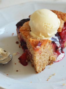 Piece of plum cake on a plate with a spoon.