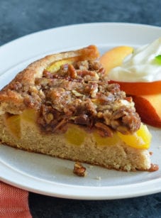 Slice of peach cake on a plate with peaches.
