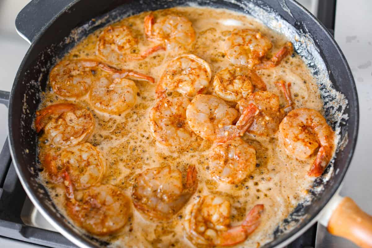 Seasoned shrimp in a skillet with melted butter. 