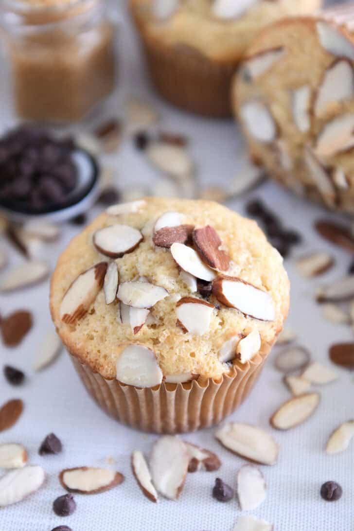 Almond coconut chocolate chip muffin on brown paper muffin liner.