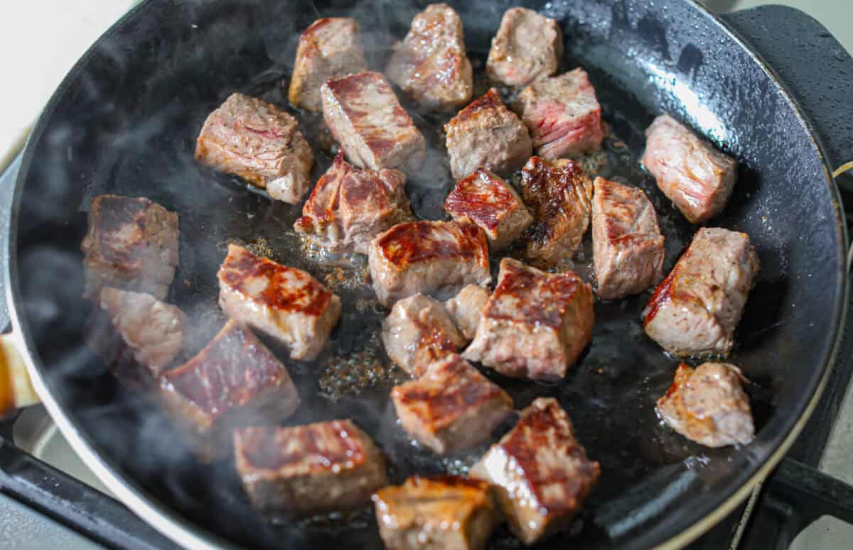 Steak bites searing in a skillet. 