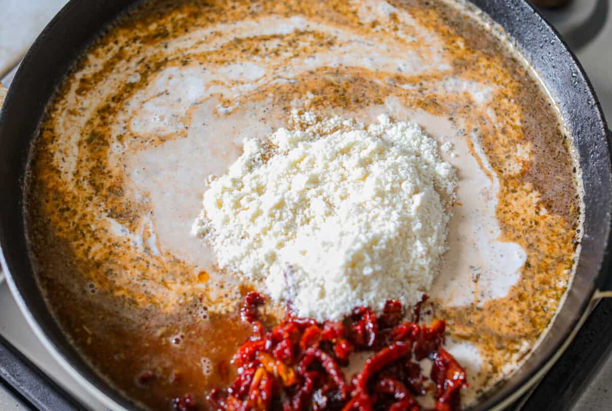 Sun-dried tomatoes, cream, and parmesan cheese added to the skillet. 