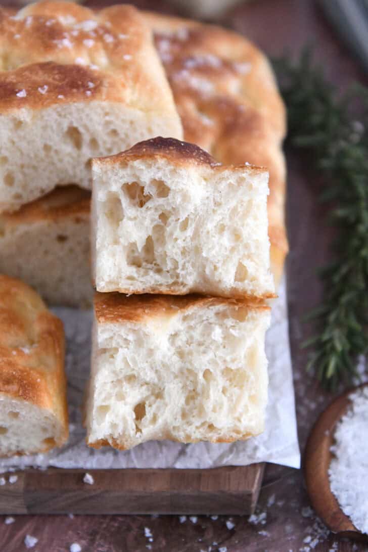Two half pieces of fluffy focaccia on white parchment paper.