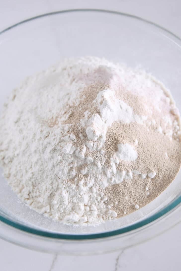 Glass bowl with flour, yeast, and salt.