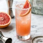 marble counter with paloma cocktail garnished with grapefruit slice