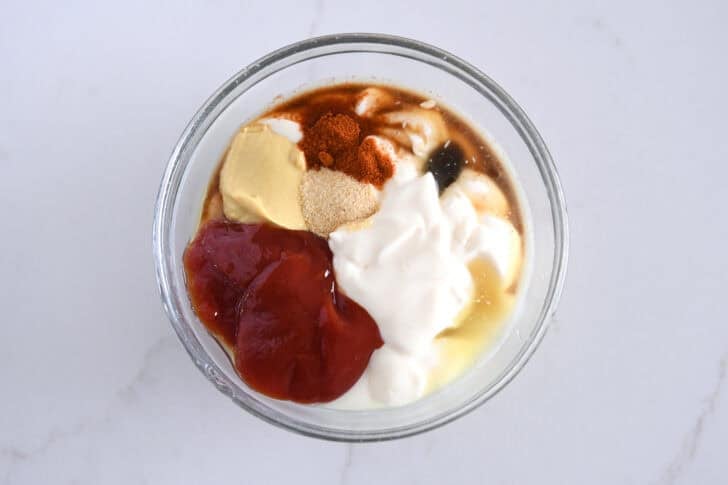 Ketchup, mayonnaise, mustard, garlic powder, Worcestershire sauce, paprika and vinegar in glass bowl.