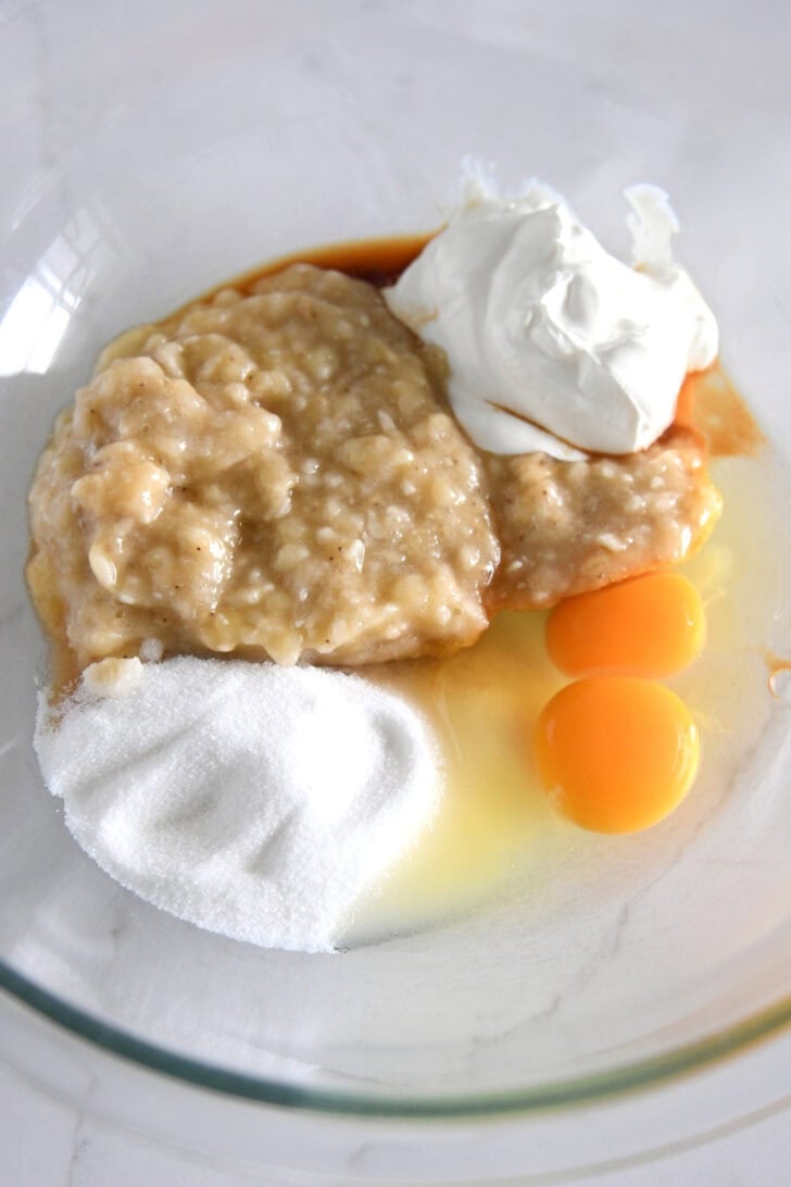 Glass bowl with mashed bananas, sugar, eggs, and sour cream.