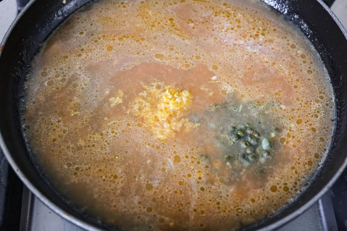 Chicken broth, lemon zest, lemon juice, and capers added to the skillet to simmer and reduce. 