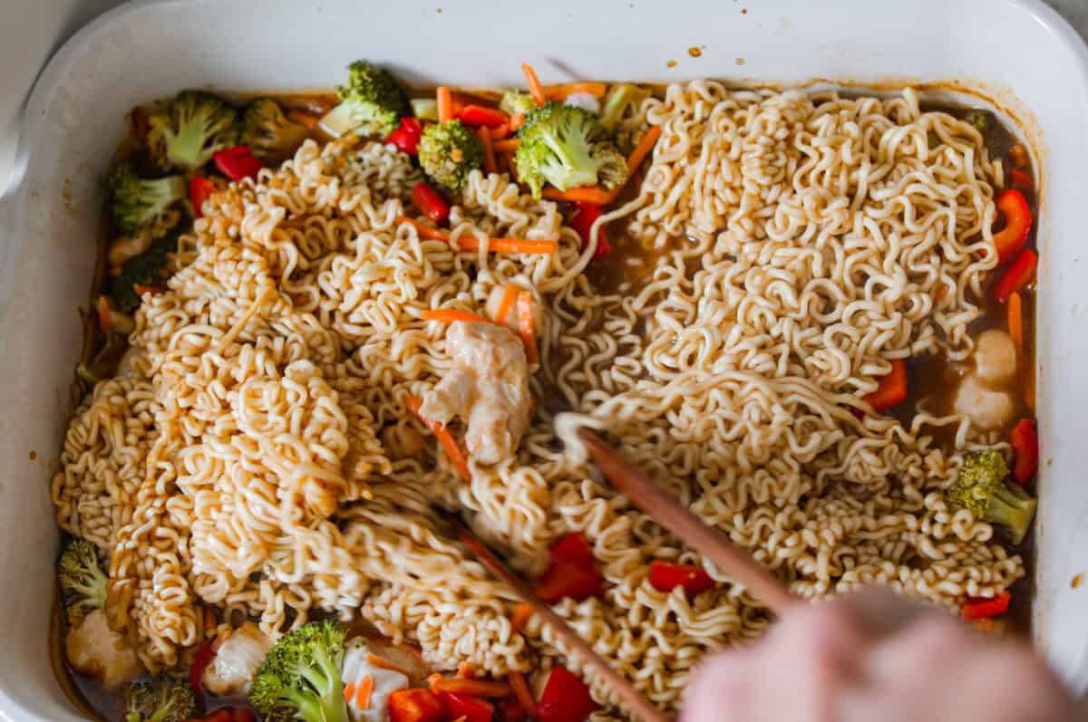Stirring the partially baked dump and bake ramen together with chopsticks. 