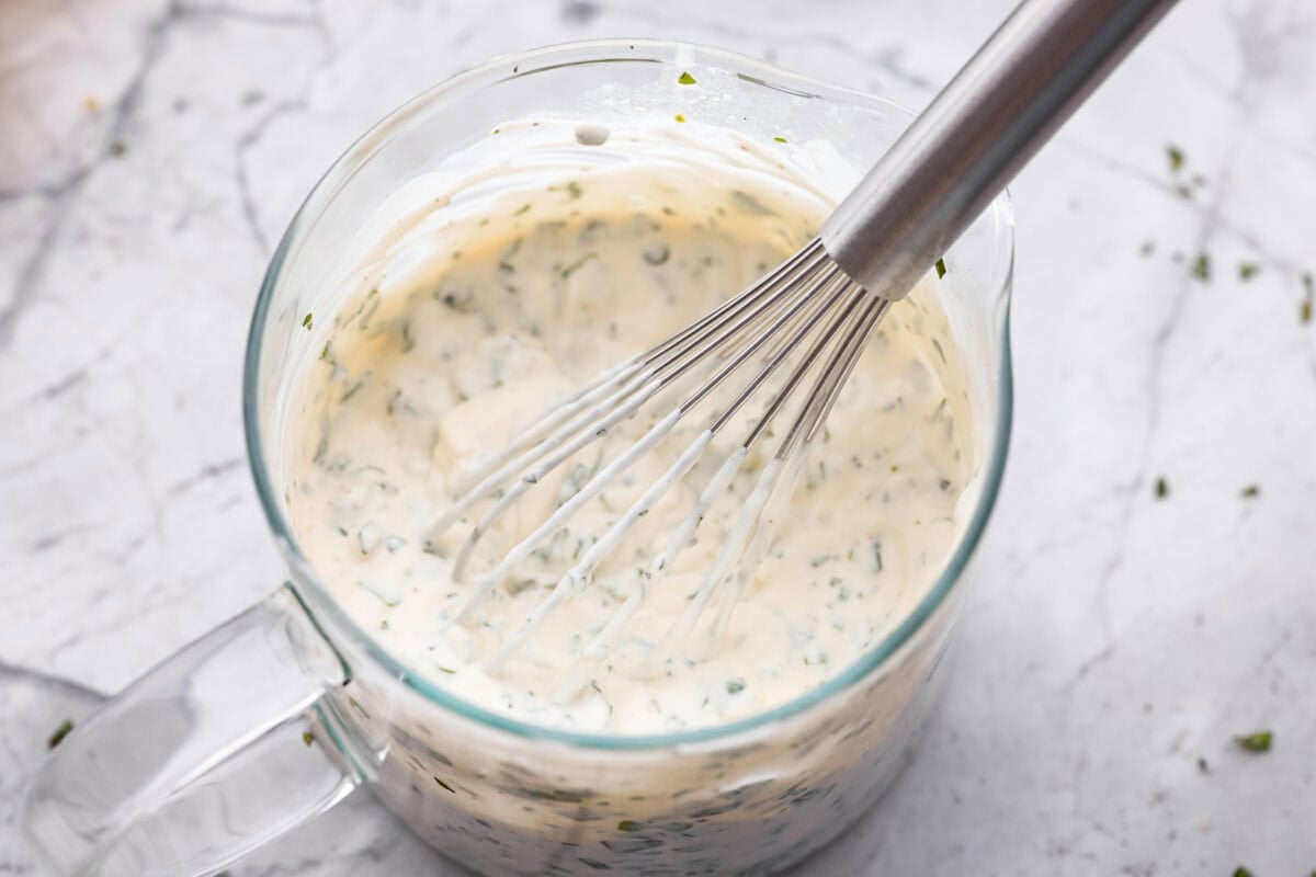 All of the dressing ingredients in a container with a whisk. 