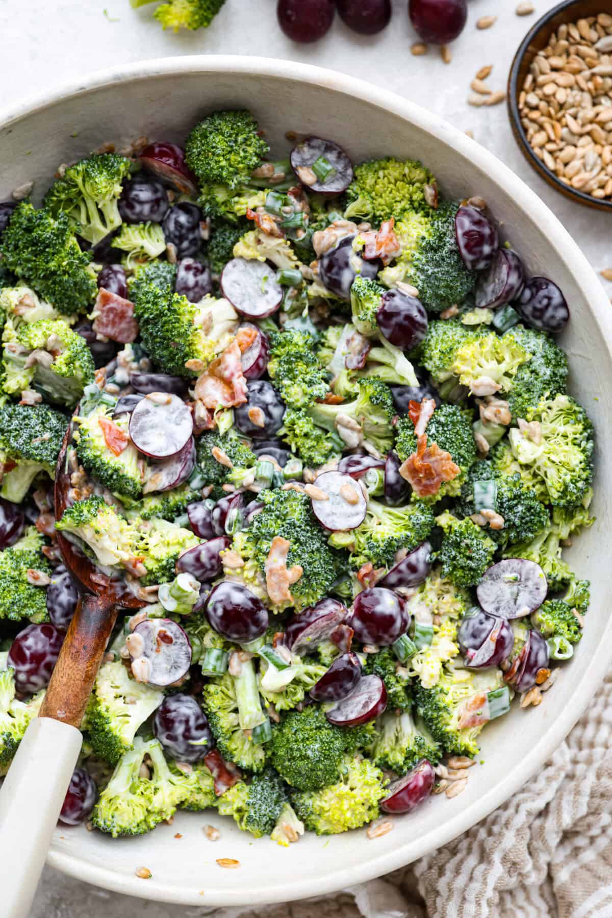 Bowl of broccoli grape salad with wooden serving spoon,. 