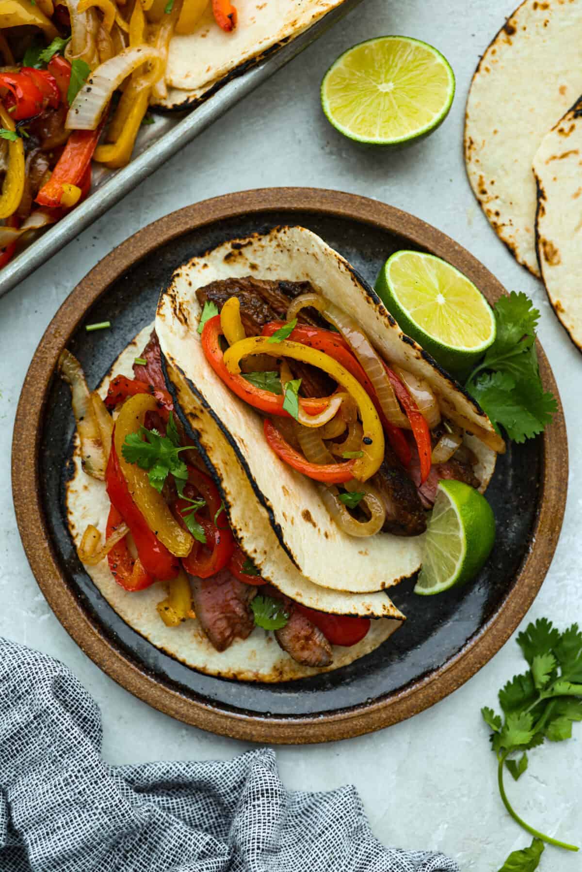Plate with two tortillas filled with grilled steak fajita ingredients. 