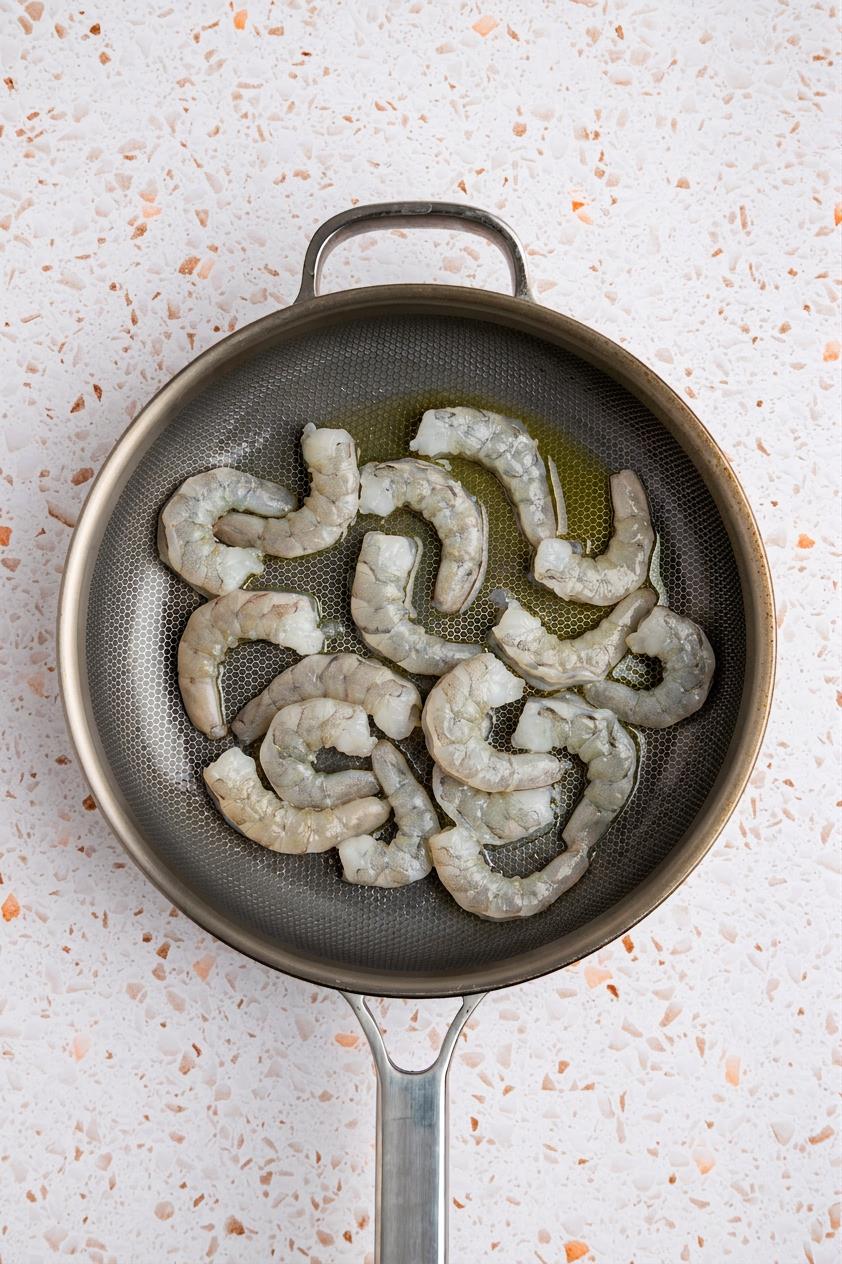Raw shrimp in skillet.