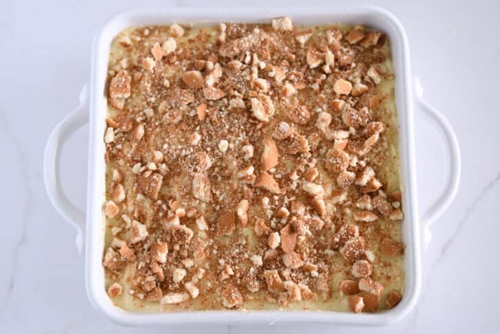 Crumbled Nilla wafers on top of vanilla pudding in white 8X8 pan.