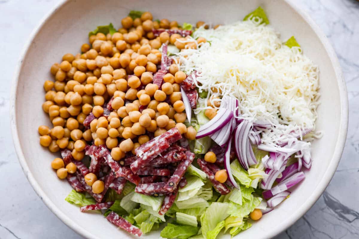 Salad ingredients added to a large bowl. 