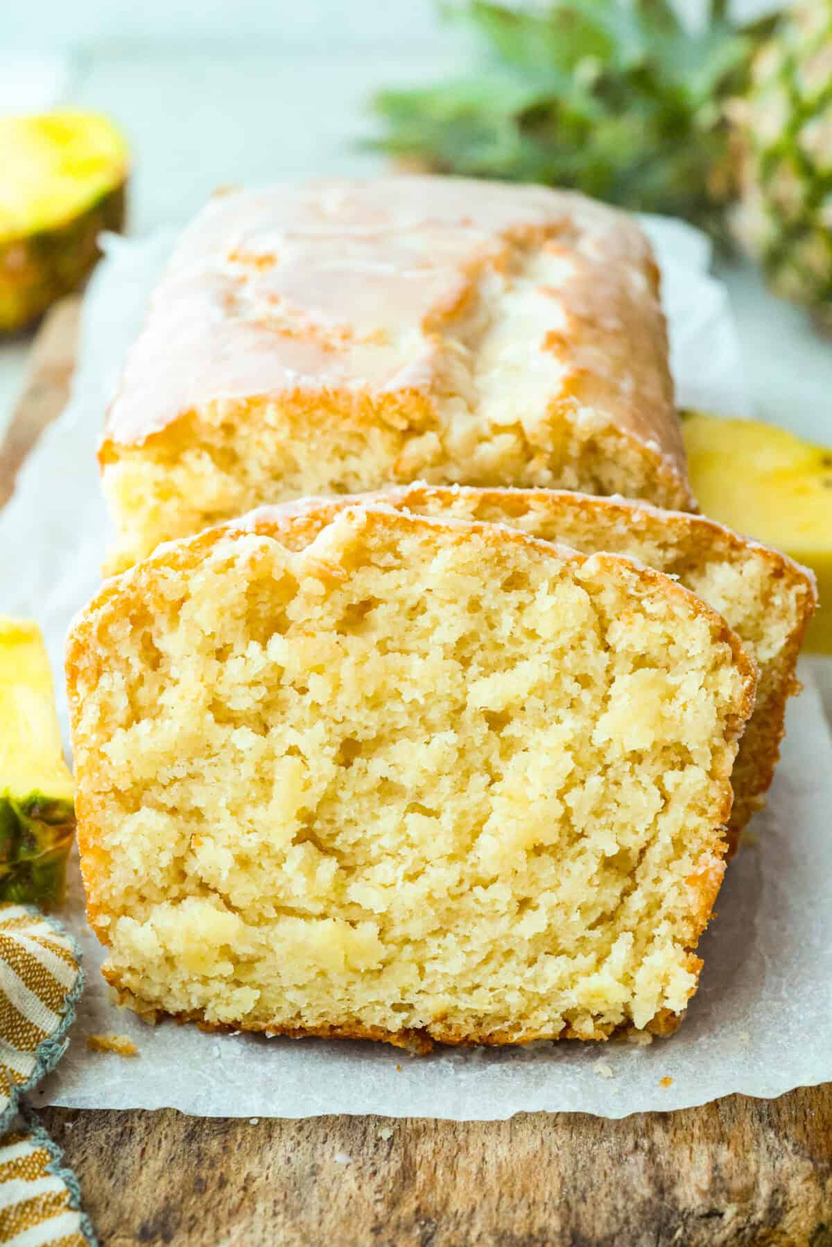 Sliced glazed pineapple bread on a cutting board. 