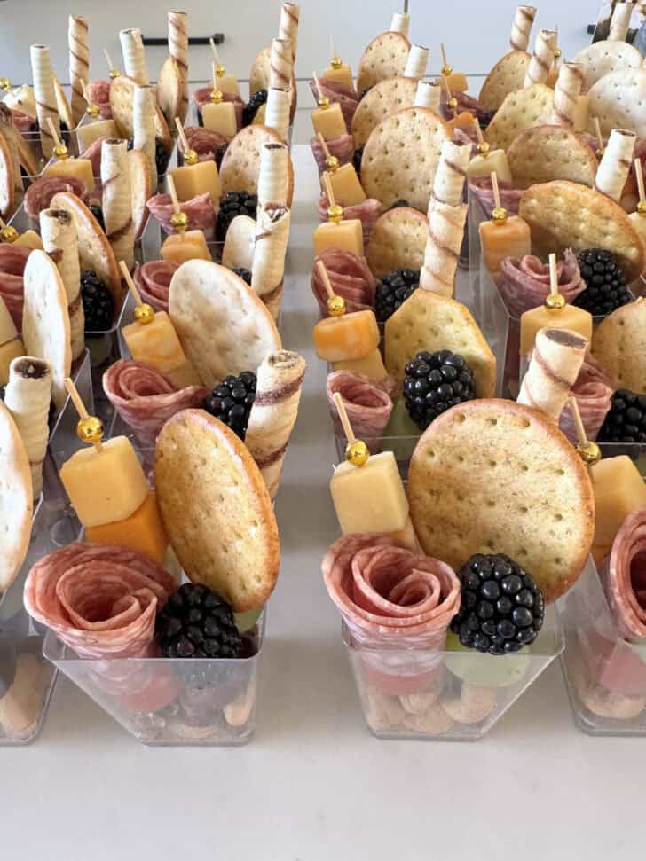 Mini charcuterie cups on white counter.