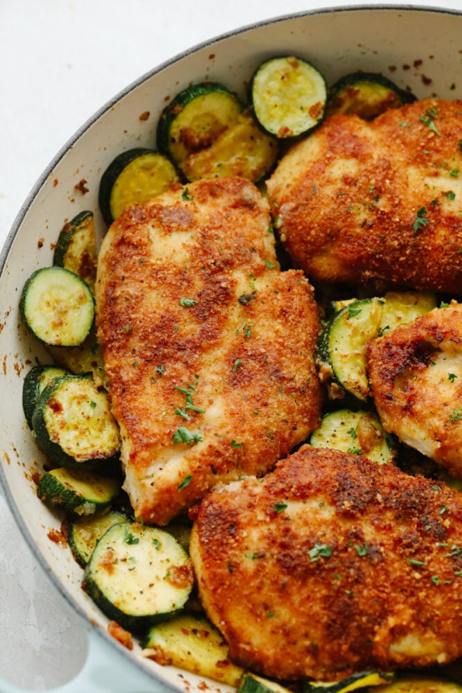 Cooked parmesan garlic chicken with zucchini in a white bowl.