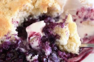 Triple berry cobbler on white plate with vanilla ice cream.