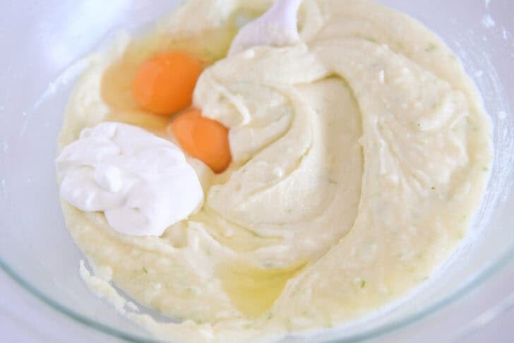 Glass bowl with mixed butter, lime zest, sugar, eggs, oil and sour cream.