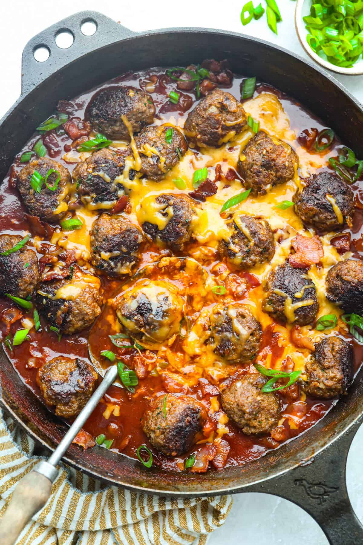 Skillet with cheesy, saucy cowboy meatballs. 
