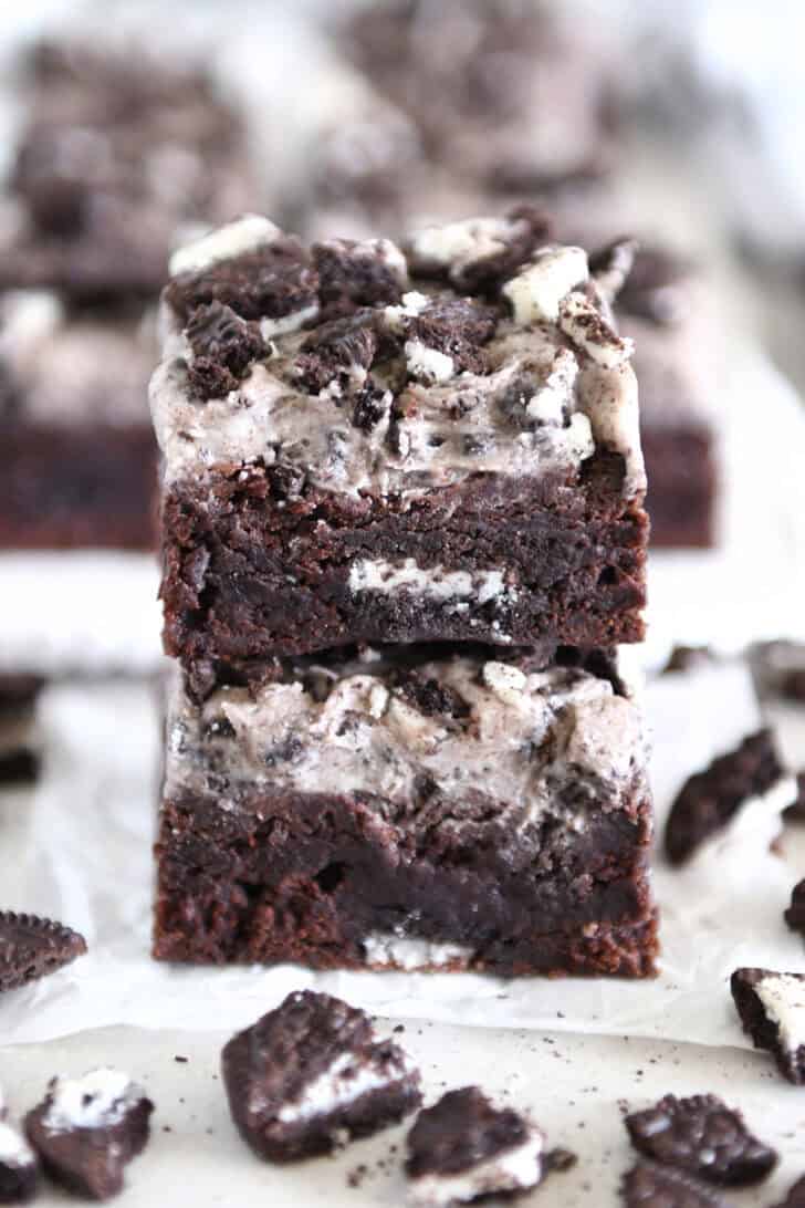 Two Oreo frosted brownies stacked on white parchment paper.