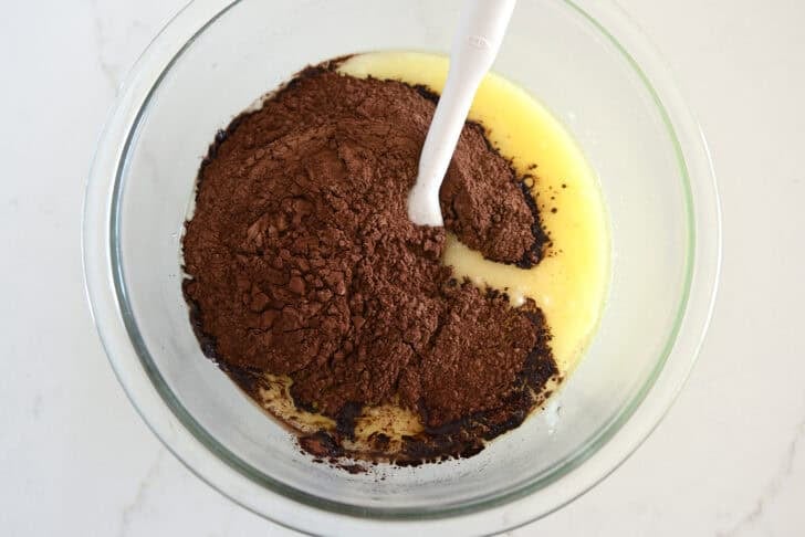 Glass bowl with melted butter, sugar and cocoa powder.