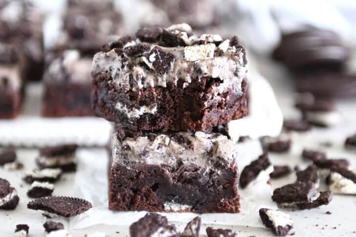 Two cookies and cream brownies stacked with bite taken out of top brownie.