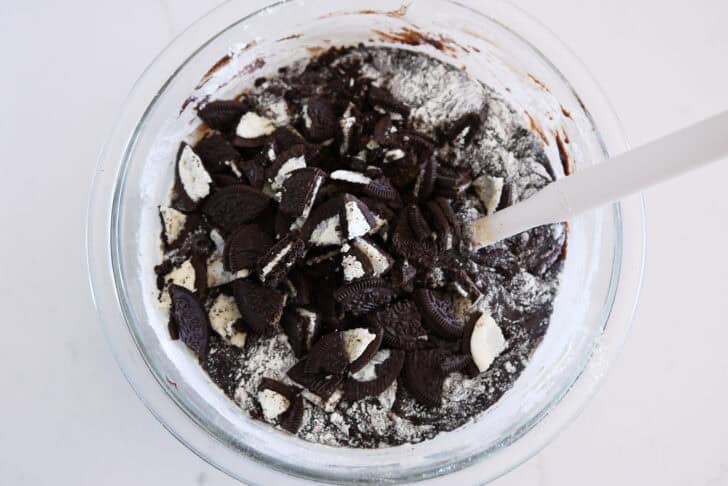 Glass bowl with brownie batter and chopped Oreos.
