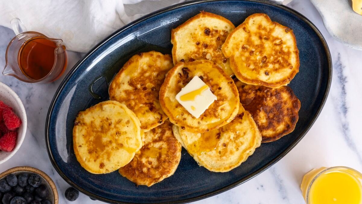 blue oval patter with cottage cheese pancakes top with a pat of butter and drizzle of maple syrup