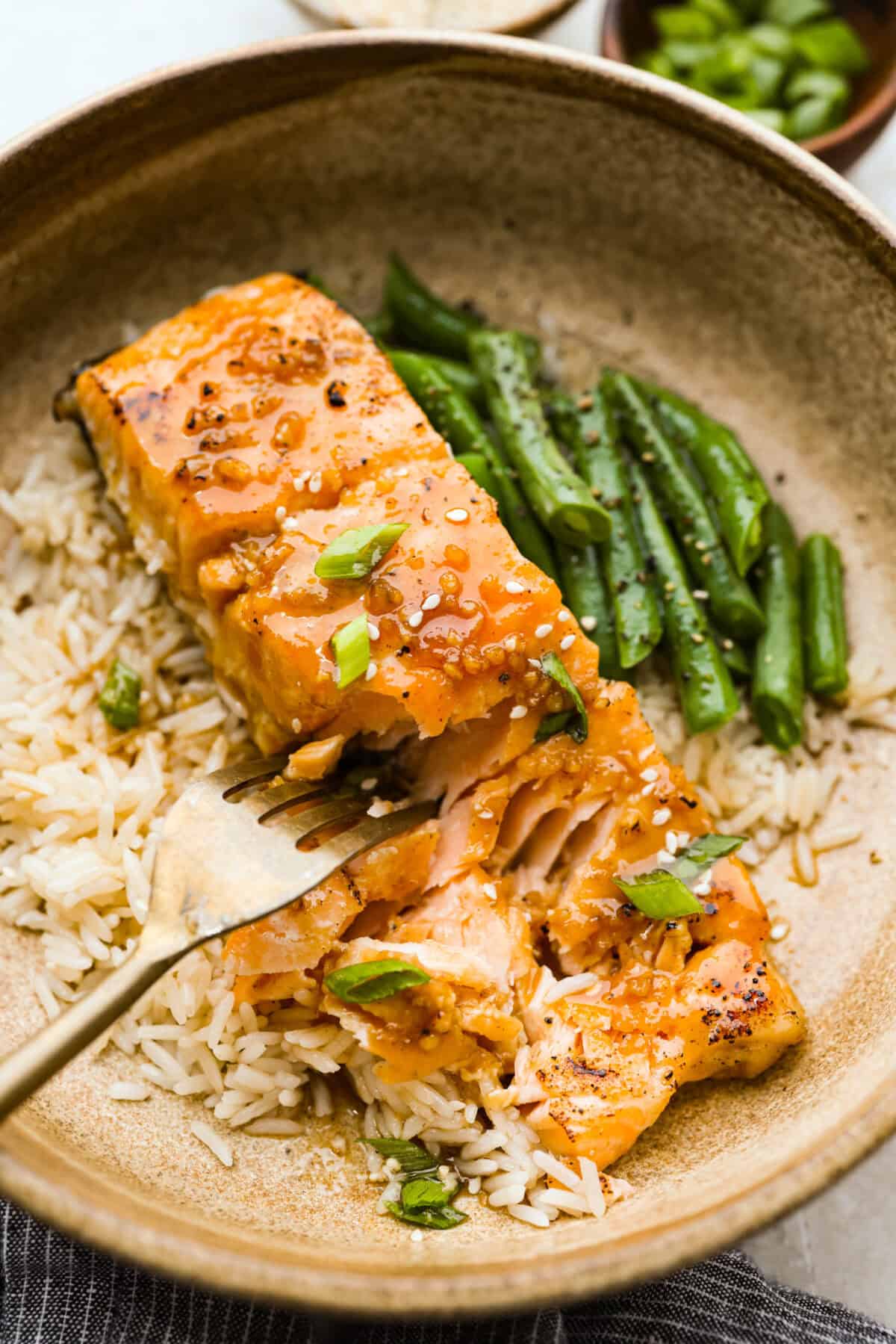 Plated maple glazed salmon on a bed of white rice and a side of green beans. 