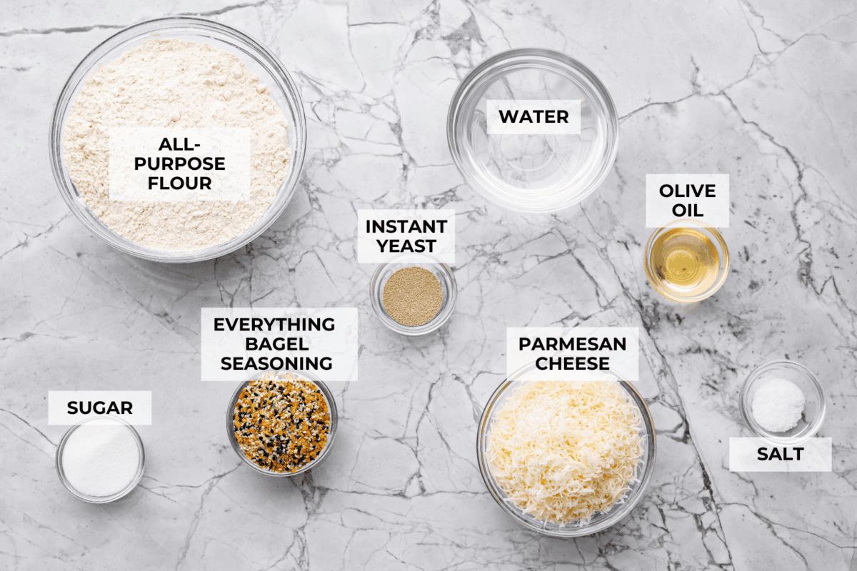 Overhead shot of labeled everything bagel pull apart bread ingredients. 