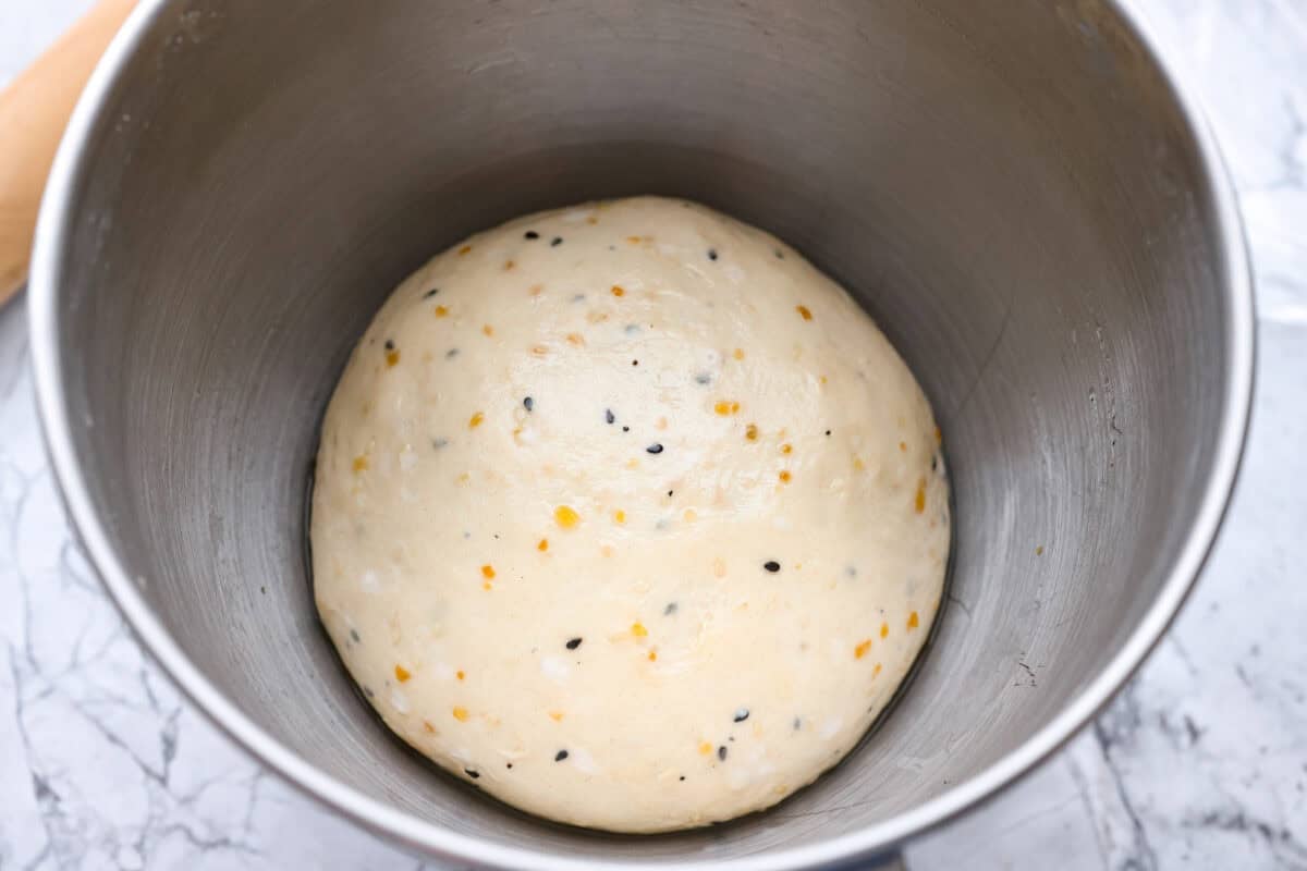 Dough ingredients mixed together rolled into a ball and left to rise in a bowl. 