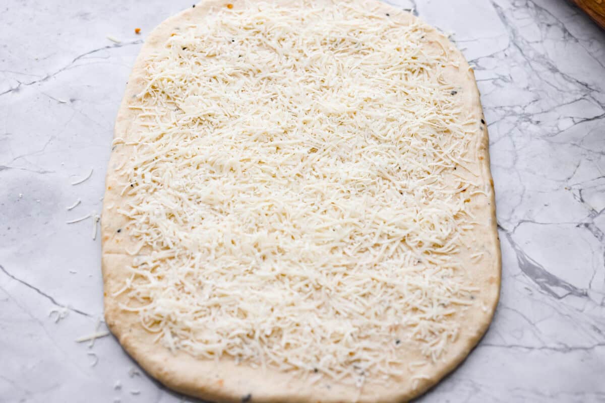 Dough rolled out into a rectangle and covered with parmesan cheese. 
