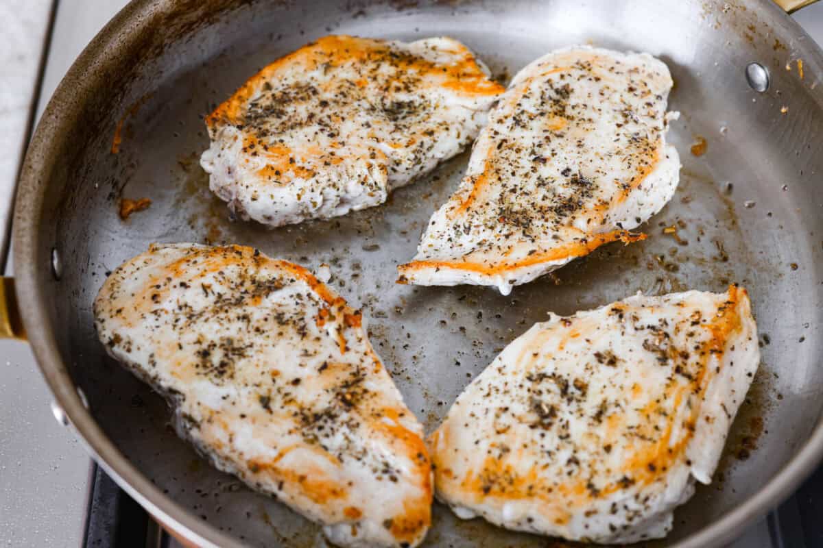 Chicken breast cooking in a skillet. 