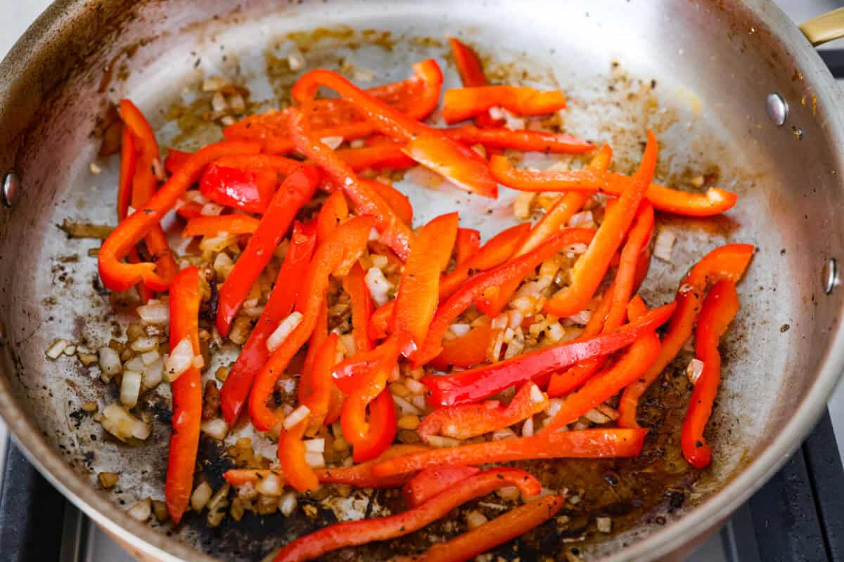 Peppers and onions cooking in a skillet. 