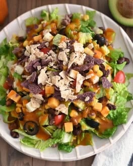 Top down view of White ridged plate with chopped taco salad and drizzled with homemade catalina dressing.